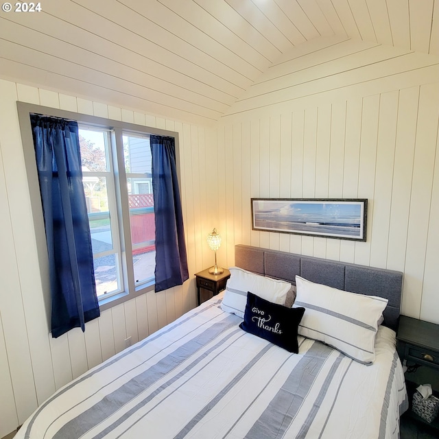 bedroom with wooden walls, lofted ceiling, and wood ceiling