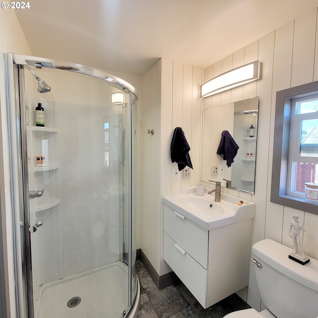 bathroom featuring vanity, toilet, and a shower with door