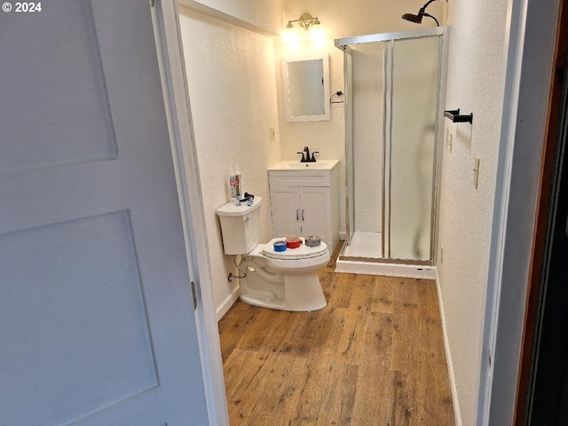 bathroom featuring walk in shower, hardwood / wood-style floors, vanity, and toilet