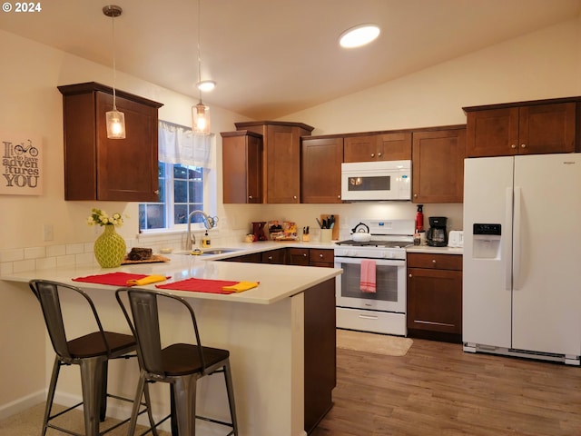 kitchen featuring kitchen peninsula, white appliances, decorative light fixtures, and sink