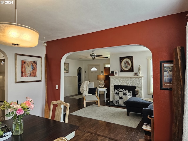 dining area featuring dark hardwood / wood-style flooring, a stone fireplace, and ceiling fan