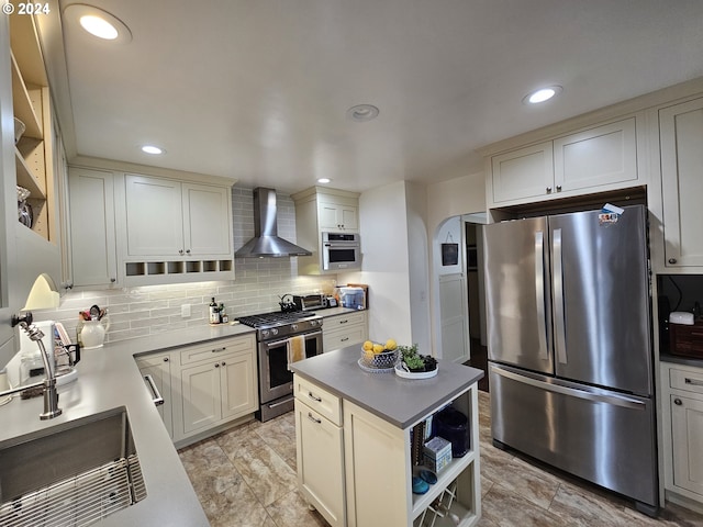 kitchen featuring sink, wall chimney exhaust hood, backsplash, a kitchen island, and appliances with stainless steel finishes