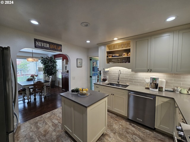 kitchen with sink, a center island, tasteful backsplash, decorative light fixtures, and appliances with stainless steel finishes