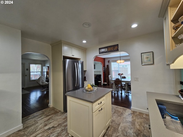 kitchen featuring decorative light fixtures, stainless steel fridge, wood-type flooring, and cream cabinets