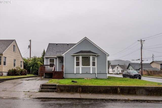 bungalow-style house with a residential view, roof with shingles, stairs, a deck, and a front lawn