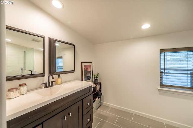 bathroom featuring vanity, baseboards, vaulted ceiling, and recessed lighting