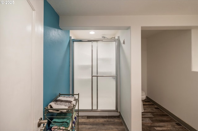 full bath featuring a shower stall, baseboards, and wood finished floors