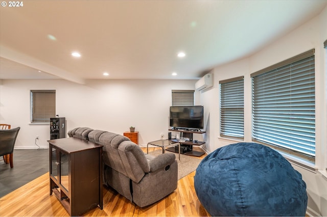 living room featuring baseboards, beamed ceiling, wood finished floors, an AC wall unit, and recessed lighting