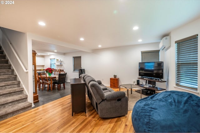 living area with a wall unit AC, stairs, wood finished floors, and recessed lighting