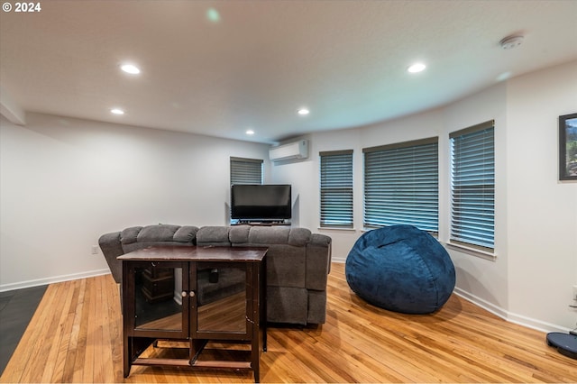 living area with baseboards, light wood finished floors, a wall mounted AC, and recessed lighting