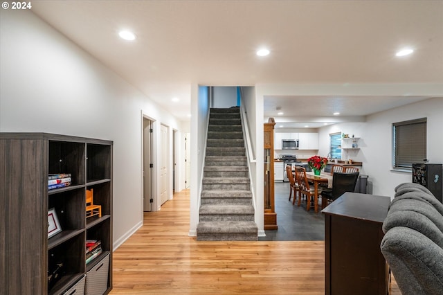 staircase with baseboards, wood finished floors, and recessed lighting