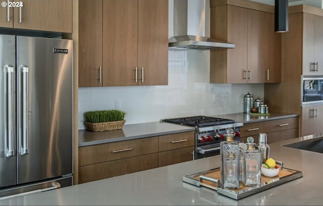 kitchen featuring high quality appliances, wall chimney range hood, and backsplash