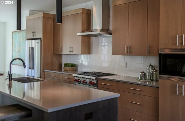 kitchen with wall chimney exhaust hood, high quality appliances, sink, and backsplash