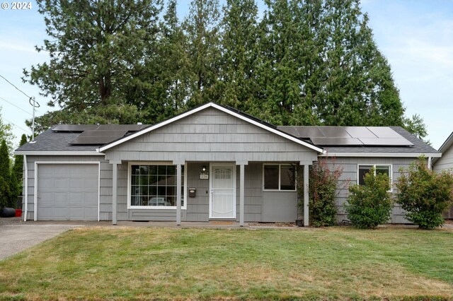 ranch-style home featuring solar panels, a garage, and a front yard