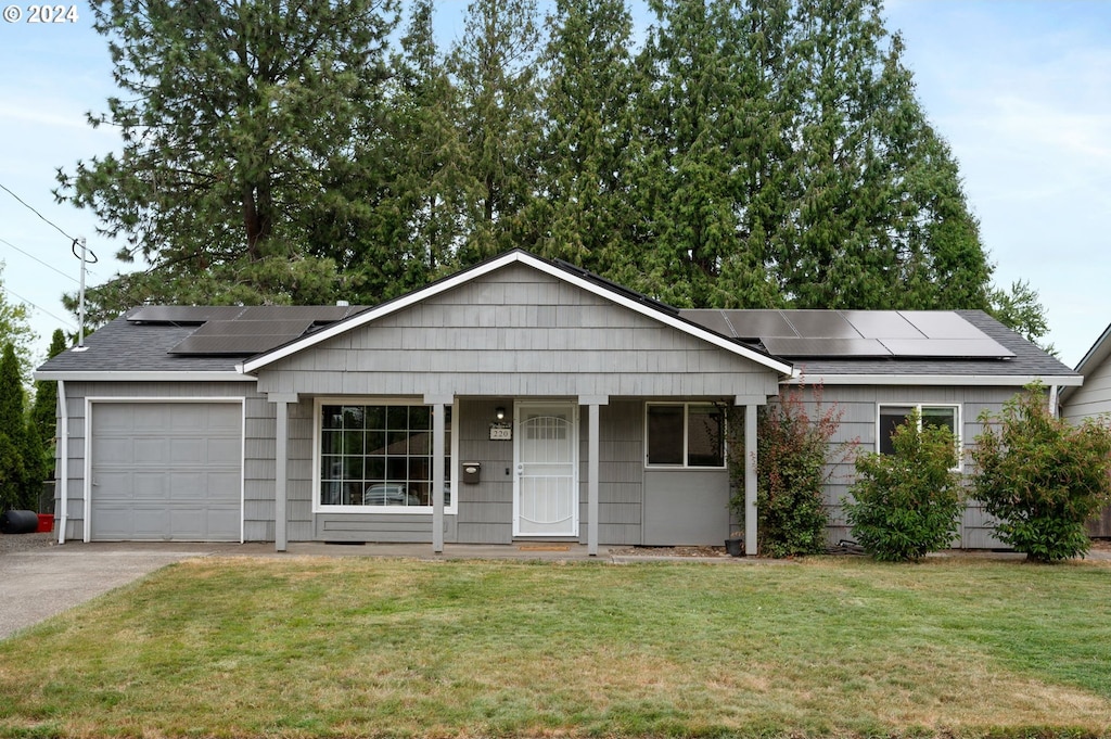 ranch-style house featuring a garage, solar panels, a porch, and a front lawn