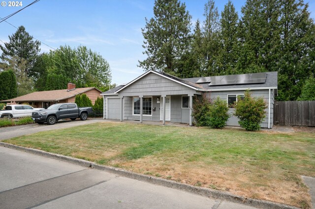 view of front facade with solar panels, a garage, and a front yard