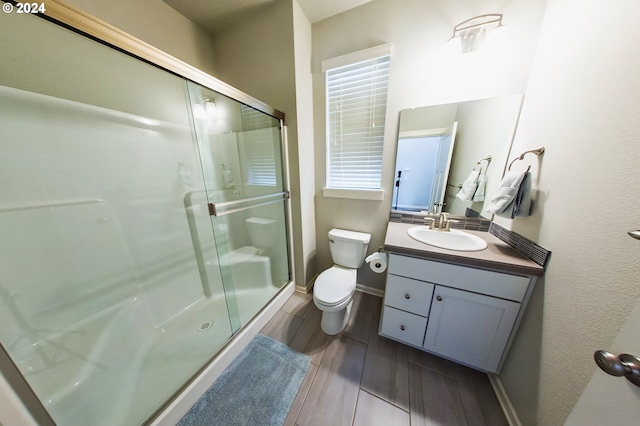 bathroom featuring hardwood / wood-style floors, vanity, toilet, and a shower with door