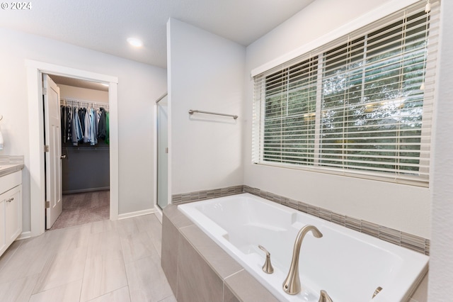 bathroom featuring tile patterned flooring, vanity, and separate shower and tub