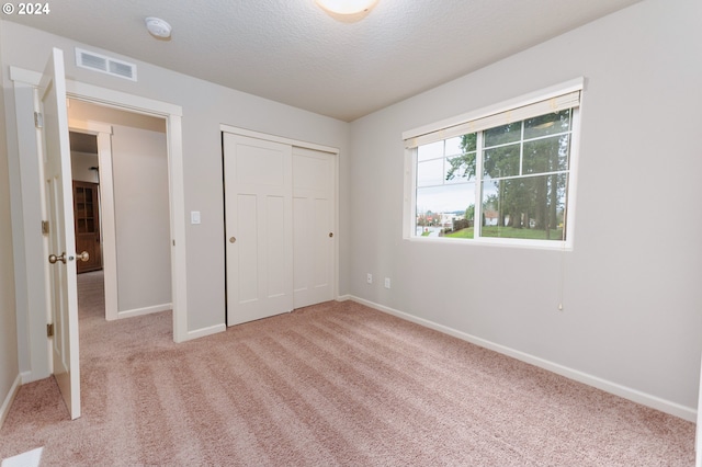 unfurnished bedroom featuring a closet, light colored carpet, and a textured ceiling