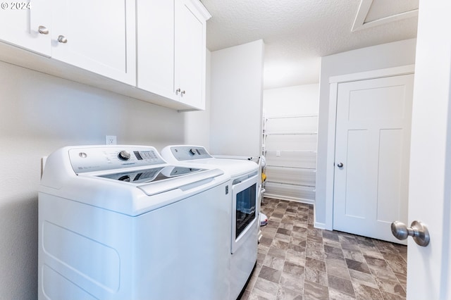 laundry room with cabinets, a textured ceiling, and washer and clothes dryer