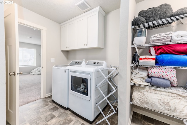 laundry area featuring a textured ceiling, cabinets, separate washer and dryer, and light carpet