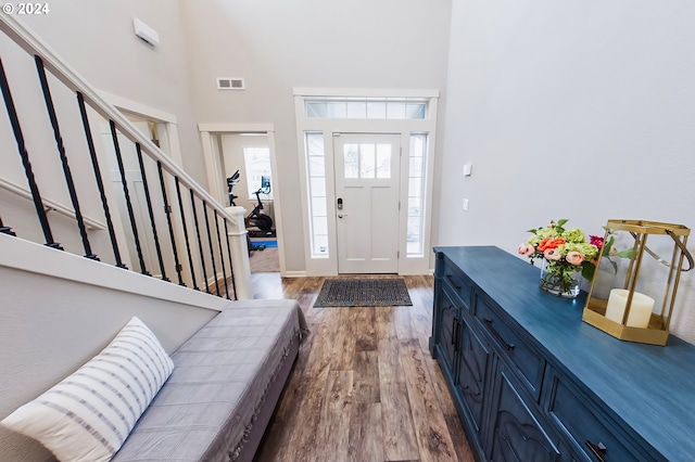 foyer entrance featuring a towering ceiling and light hardwood / wood-style flooring