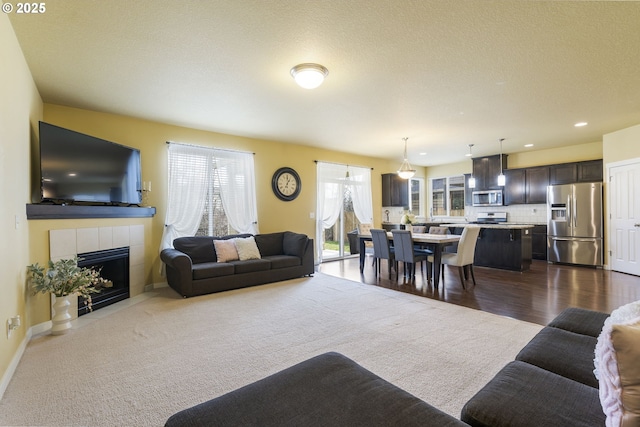 living room featuring a fireplace, a textured ceiling, and carpet flooring