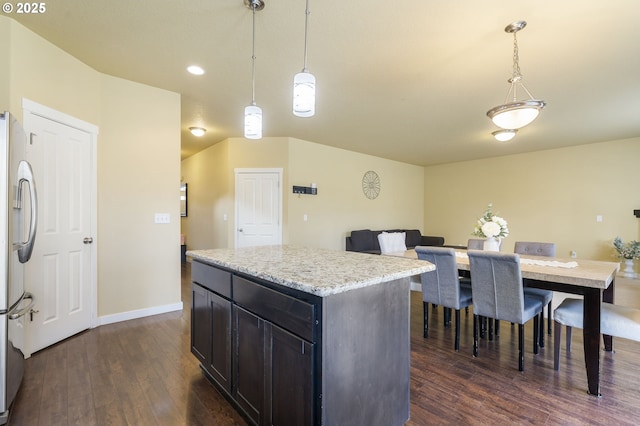 kitchen featuring dark hardwood / wood-style flooring, decorative light fixtures, stainless steel fridge, and a kitchen island