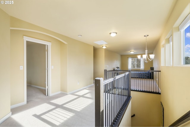 corridor featuring light colored carpet and a notable chandelier