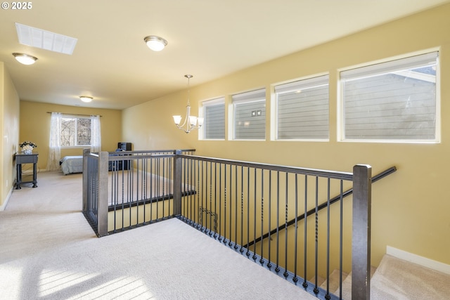 hallway featuring a notable chandelier and carpet floors