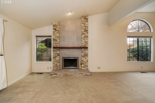 unfurnished living room with high vaulted ceiling, light colored carpet, a fireplace, and a wealth of natural light