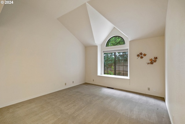 carpeted empty room featuring vaulted ceiling