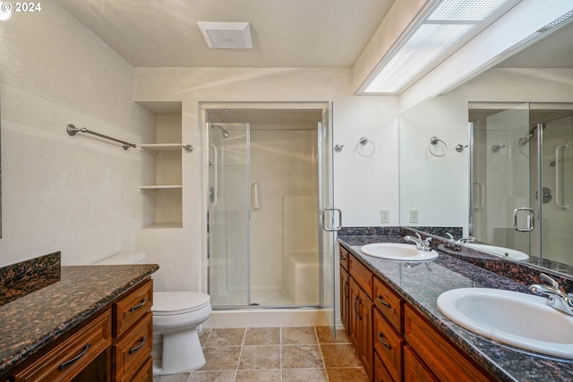 bathroom featuring tile patterned flooring, vanity, toilet, and walk in shower