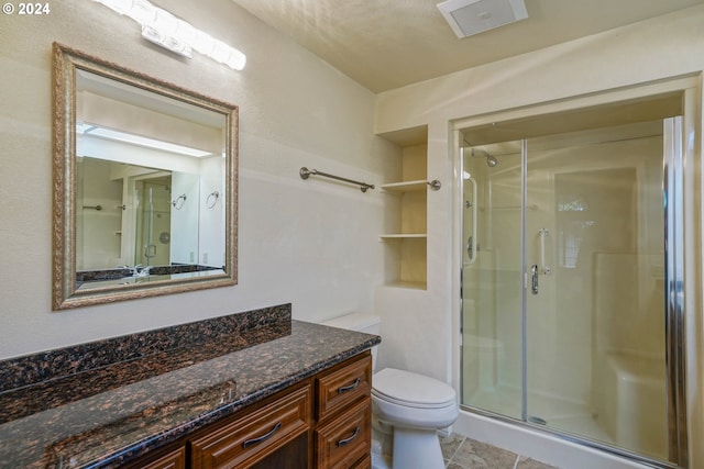 bathroom with tile patterned flooring, vanity, toilet, and walk in shower