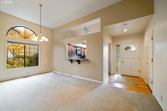 carpeted foyer with a notable chandelier