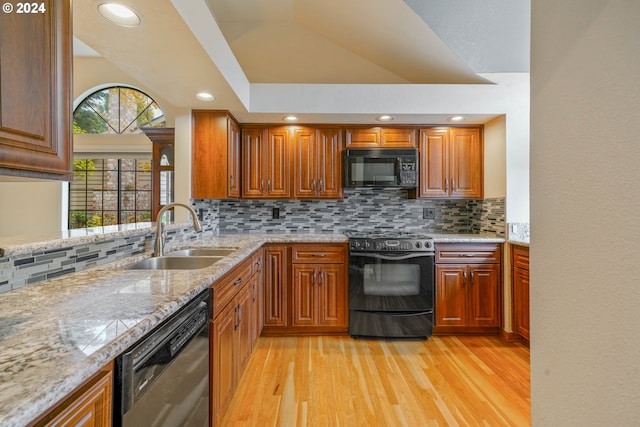 kitchen featuring tasteful backsplash, sink, black appliances, and light hardwood / wood-style floors