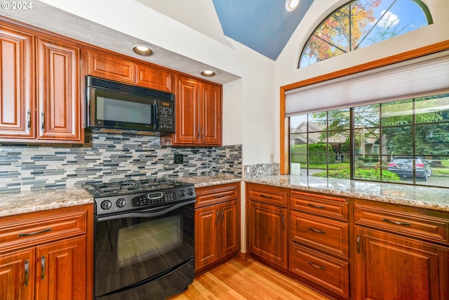 kitchen with decorative backsplash, light stone countertops, and black appliances