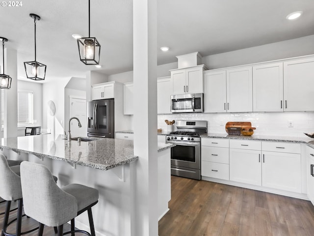 kitchen featuring white cabinets, appliances with stainless steel finishes, and hanging light fixtures