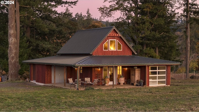 back house at dusk featuring a yard and a patio