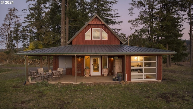 back house at dusk featuring a lawn