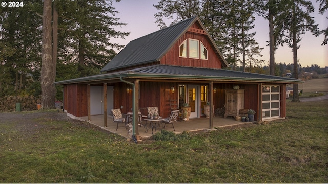 back house at dusk featuring a lawn