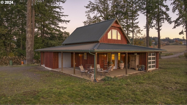 back house at dusk with a patio and a lawn