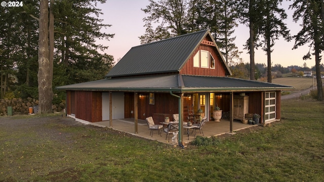 back house at dusk featuring a yard and a patio area