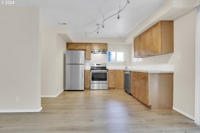 kitchen with stainless steel appliances, sink, and light hardwood / wood-style flooring