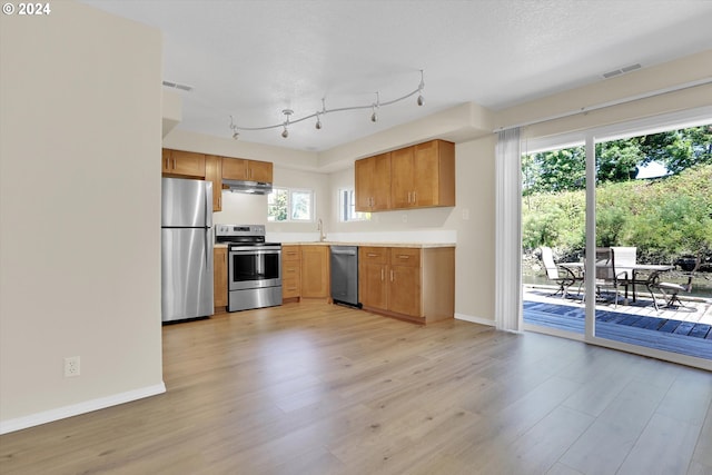 kitchen featuring appliances with stainless steel finishes, sink, a textured ceiling, and light hardwood / wood-style flooring