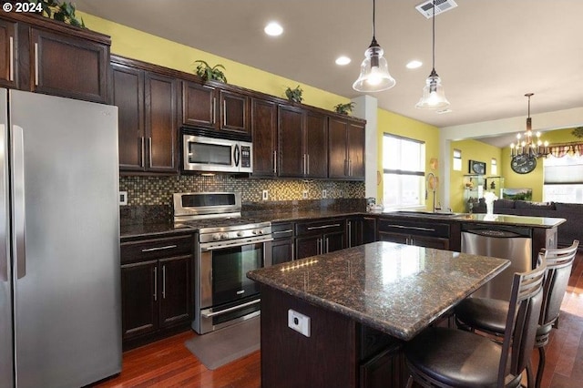 kitchen featuring appliances with stainless steel finishes, dark hardwood / wood-style flooring, backsplash, sink, and an inviting chandelier