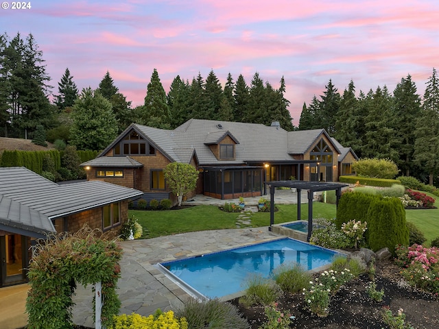 pool at dusk with a jacuzzi, a lawn, and a patio area