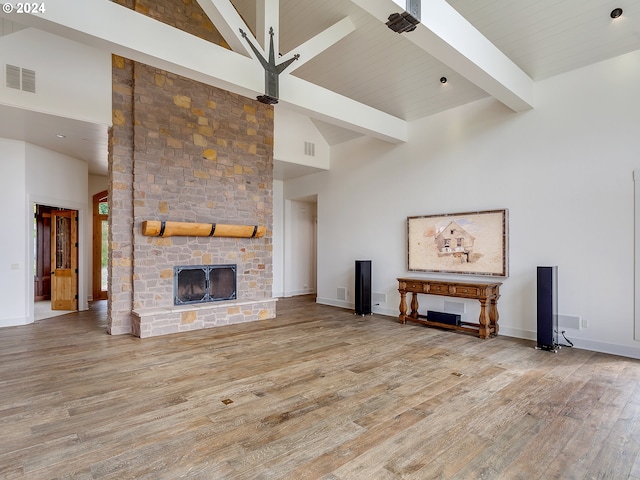 unfurnished living room featuring a fireplace, high vaulted ceiling, beam ceiling, and light hardwood / wood-style floors