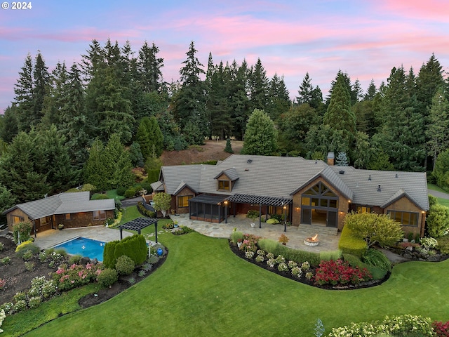 exterior space with an outdoor fire pit, a yard, a tiled roof, an outdoor pool, and a patio area