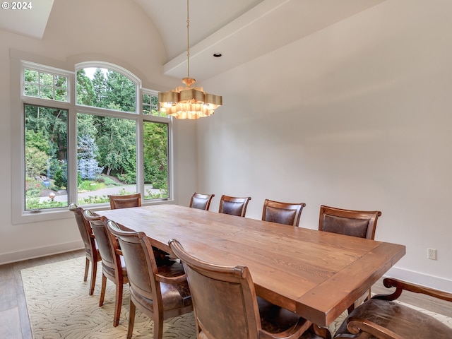 dining space with hardwood / wood-style floors, high vaulted ceiling, and an inviting chandelier